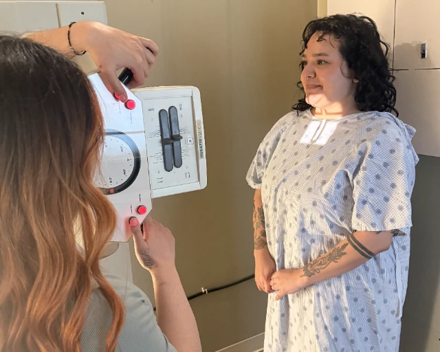 A clinic team member explains assessment equipment to a patient before an examination.
