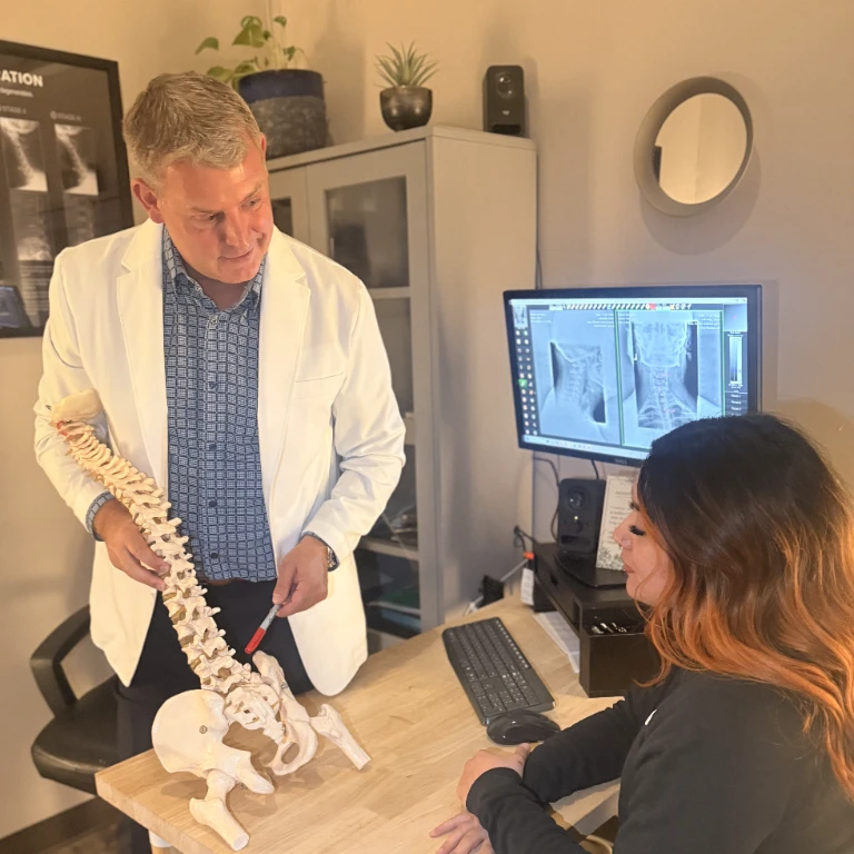 Chiropractor explaining spinal alignment with an anatomical model